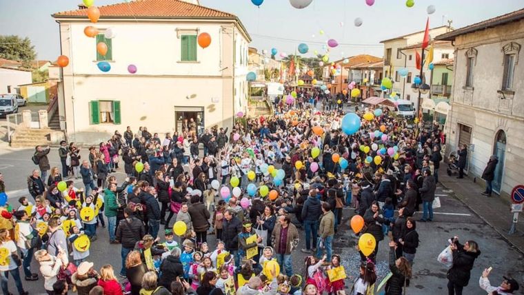 Palloncini che volano sopra una piazza piena di bambini e famiglie